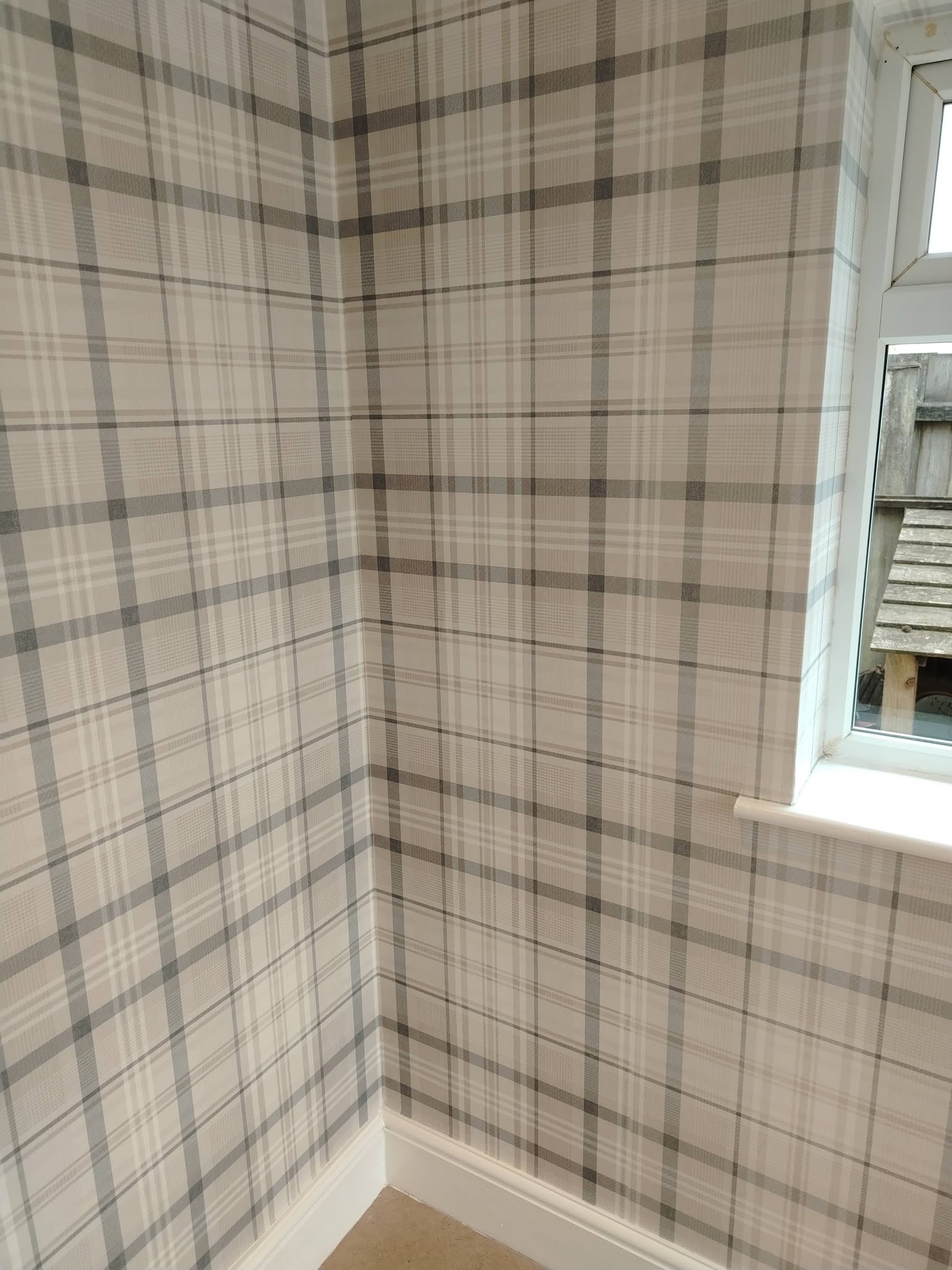Grey tartan wallpaper pattern-matched into a corner