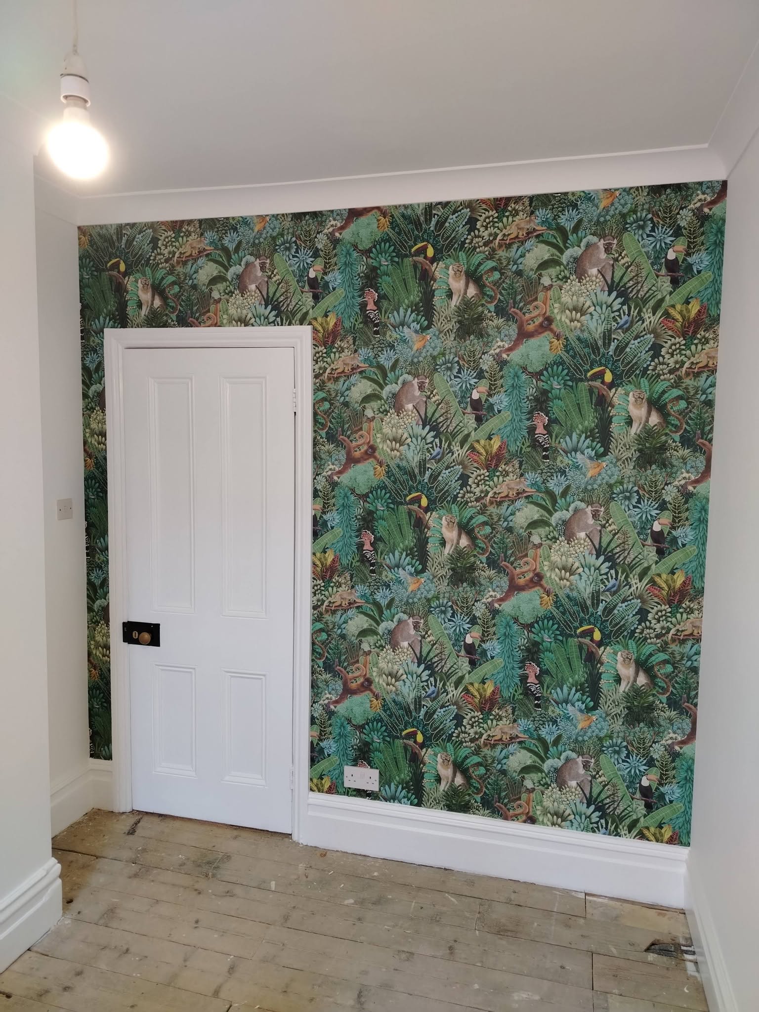 Jungle-print wallpaper hung as a feature wall around a white door