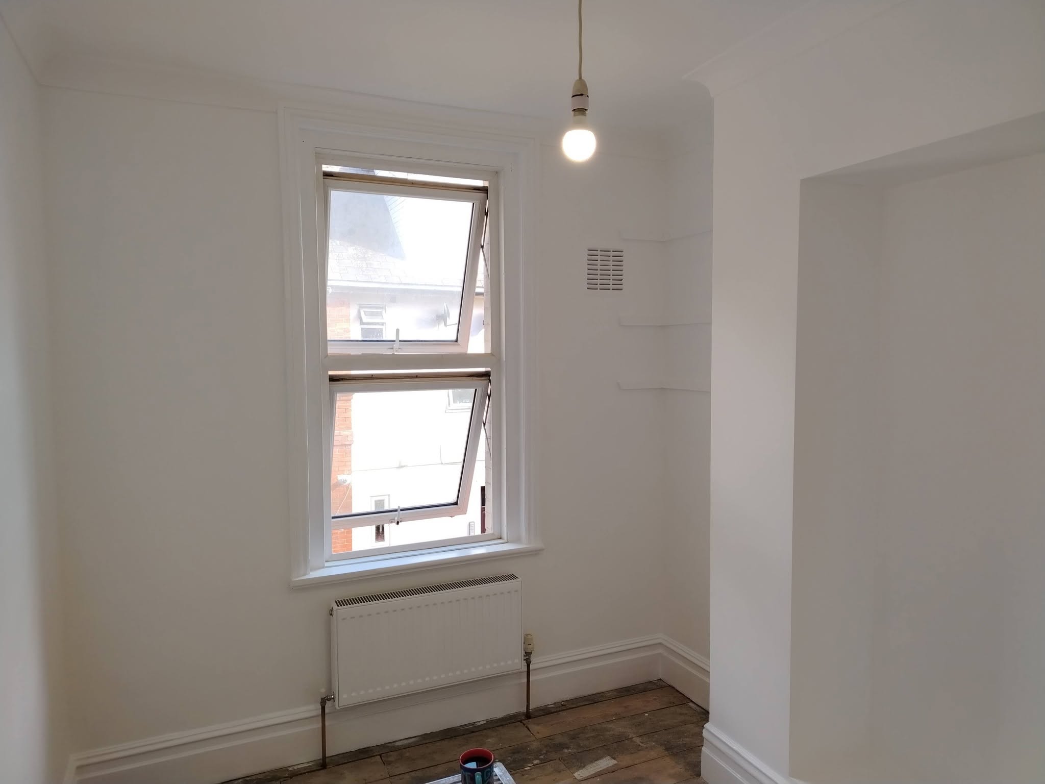 Bare room freshly painted white around a sash window