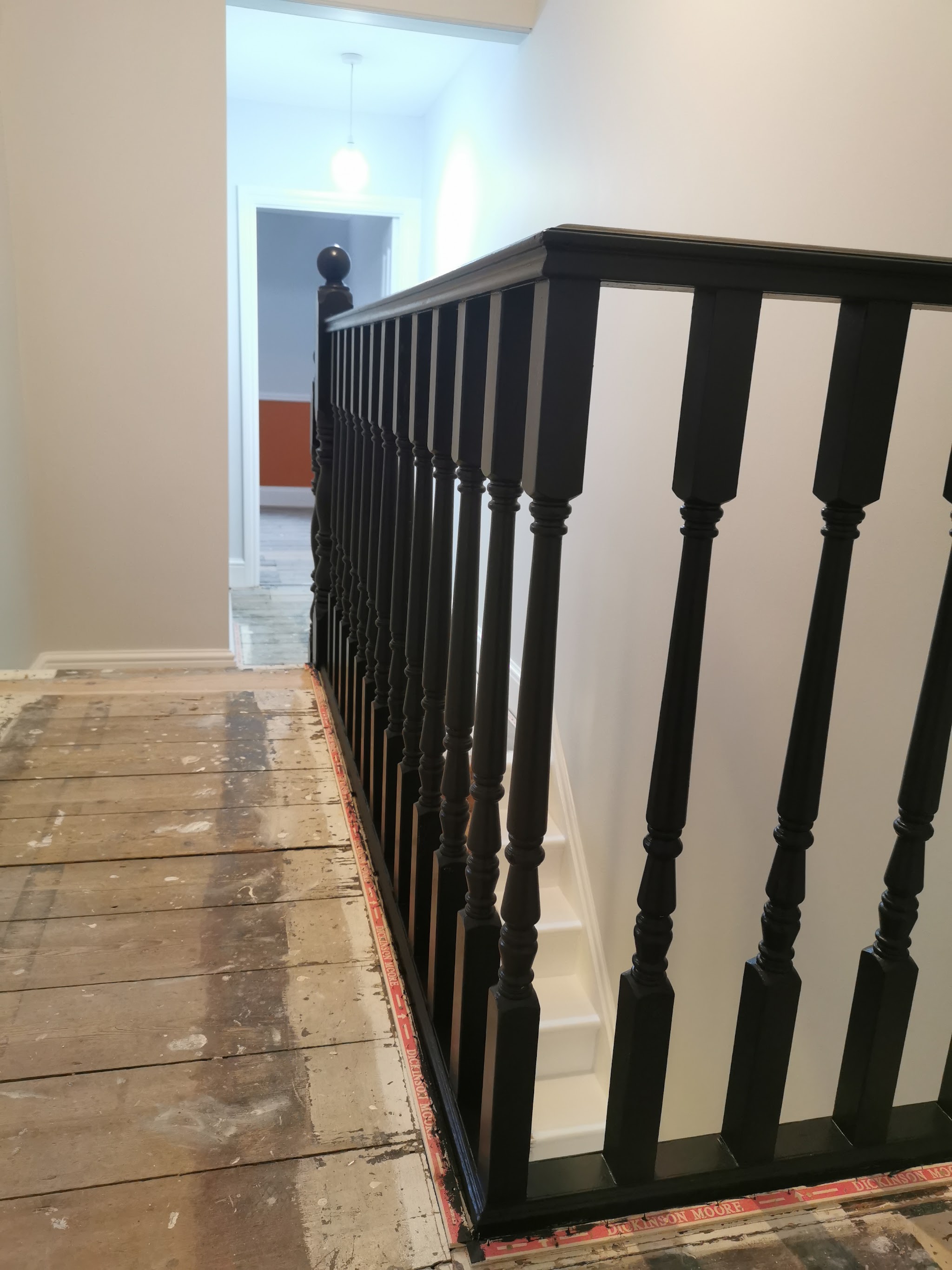 Black stair balustrade freshly painted, floor boards still bare