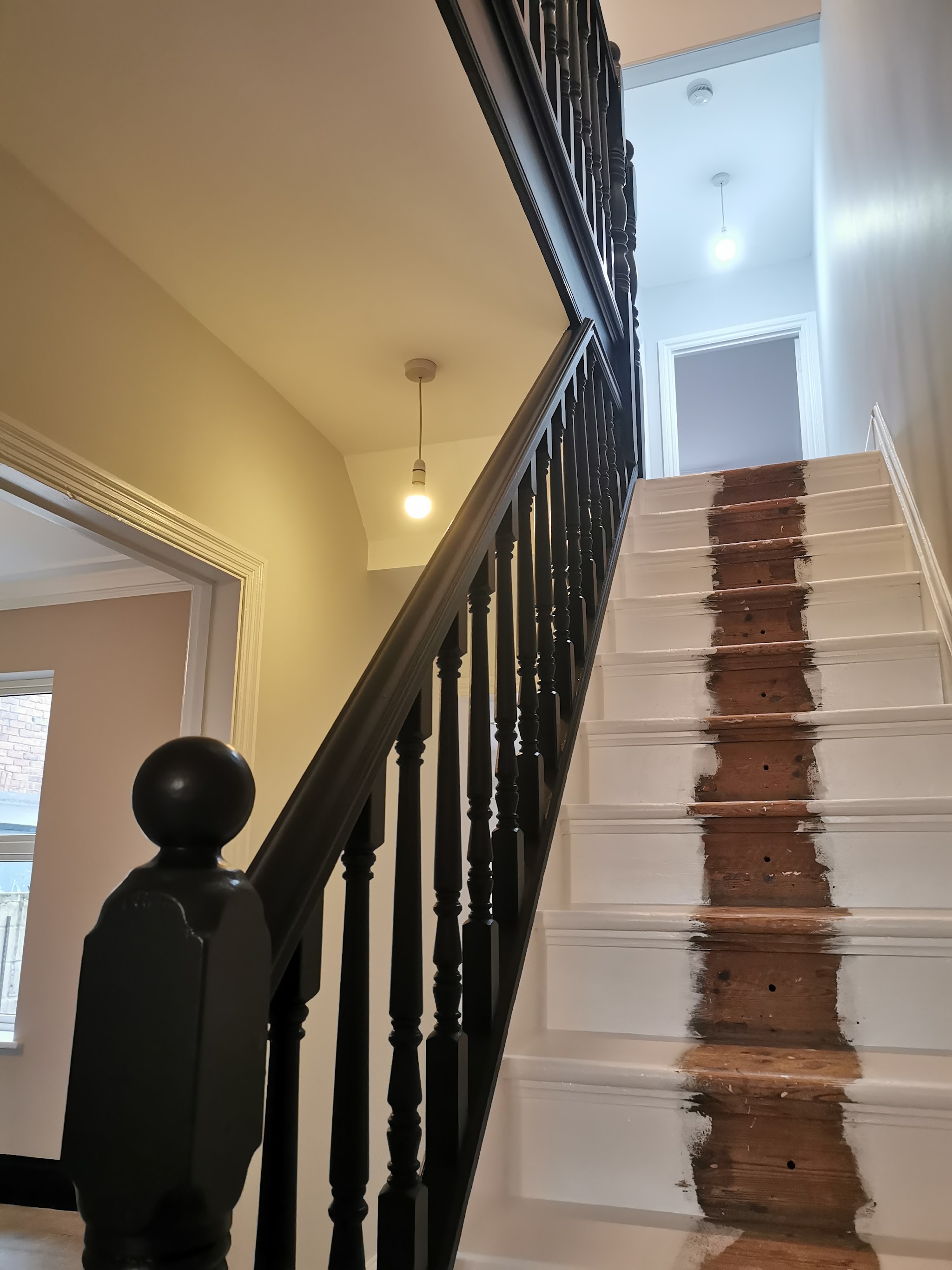 Staircase with black spindles and newel post against white walls